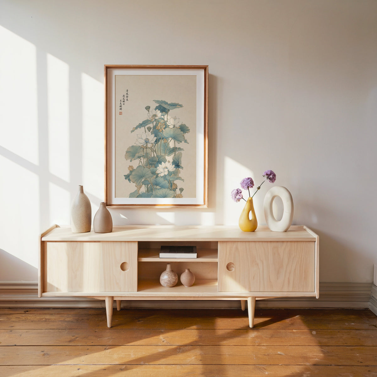 white lotus pond with verse print shown in a wood frame with a white mat above a pale wood media console
