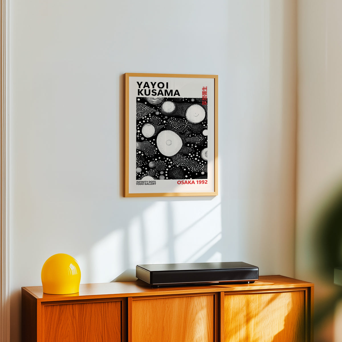 Yayoi Kusama inspired white orbs on black print above a sideboard with a yellow lamp