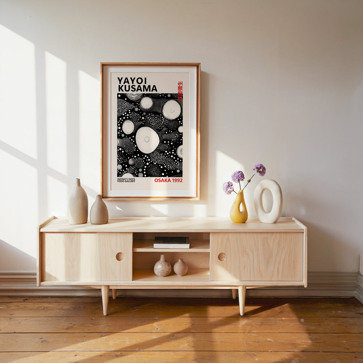 Yayoi Kusama inspired white orbs on black print above a pale wood console