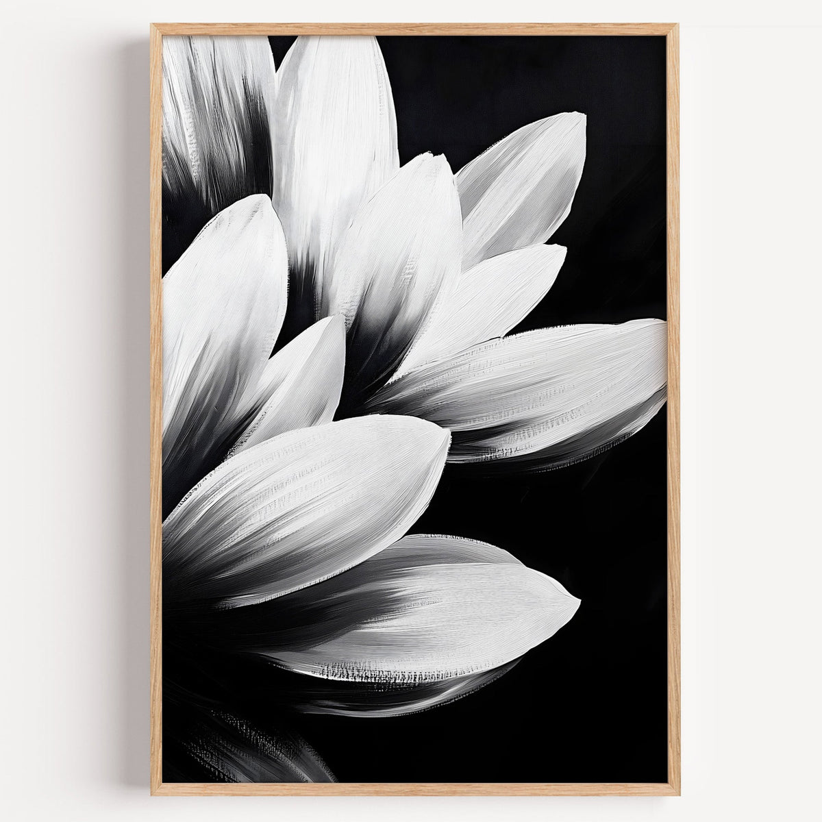White petals on black background floral print in a light oak frame on a plain white wall
