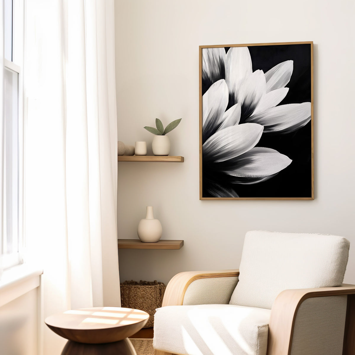 White petals on black background floral print in a slim oak frame above a cream boucle armchair by floating shelves