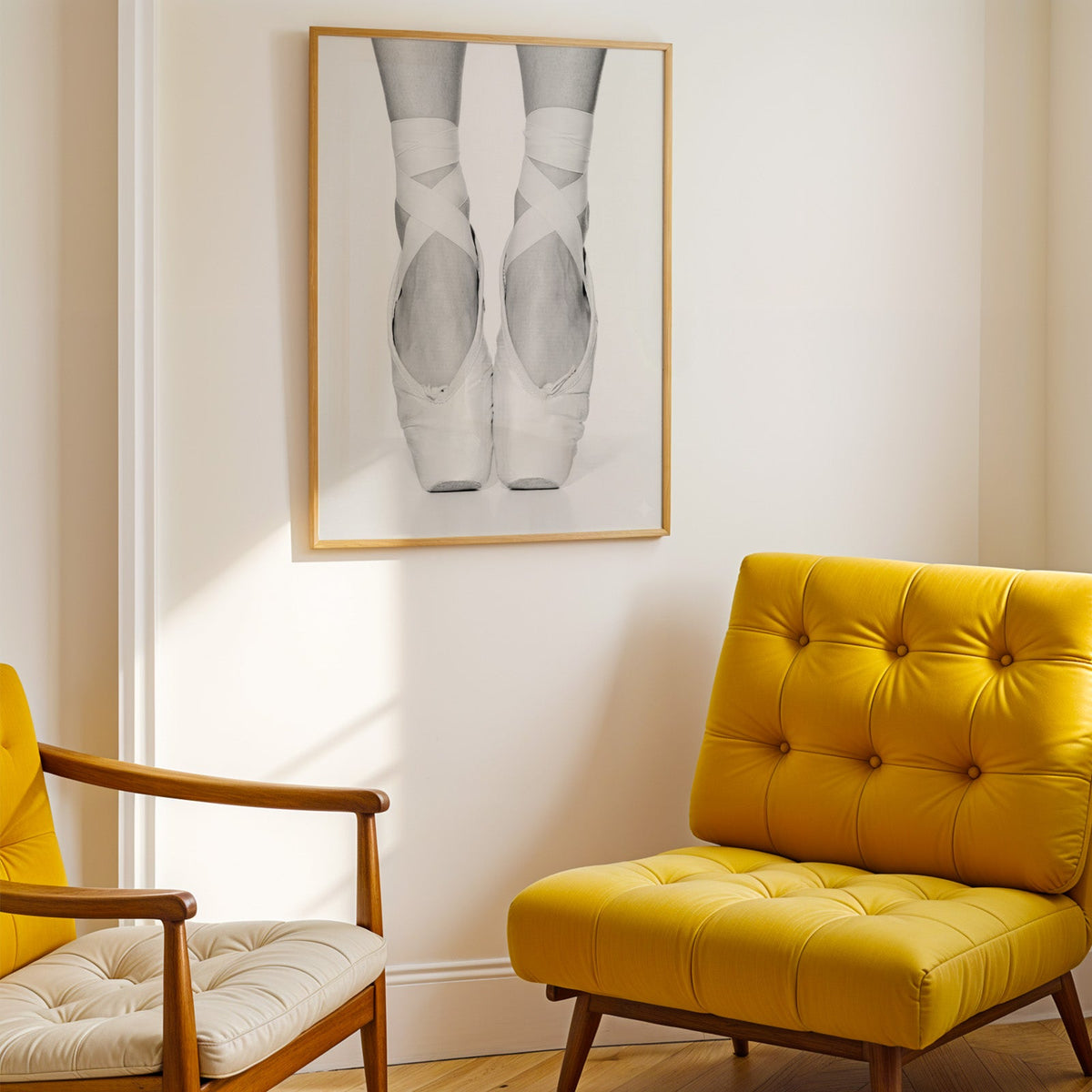 White pointe shoes with crossed ribbons close-up print shown in a gold frame above a mustard yellow tufted armchair