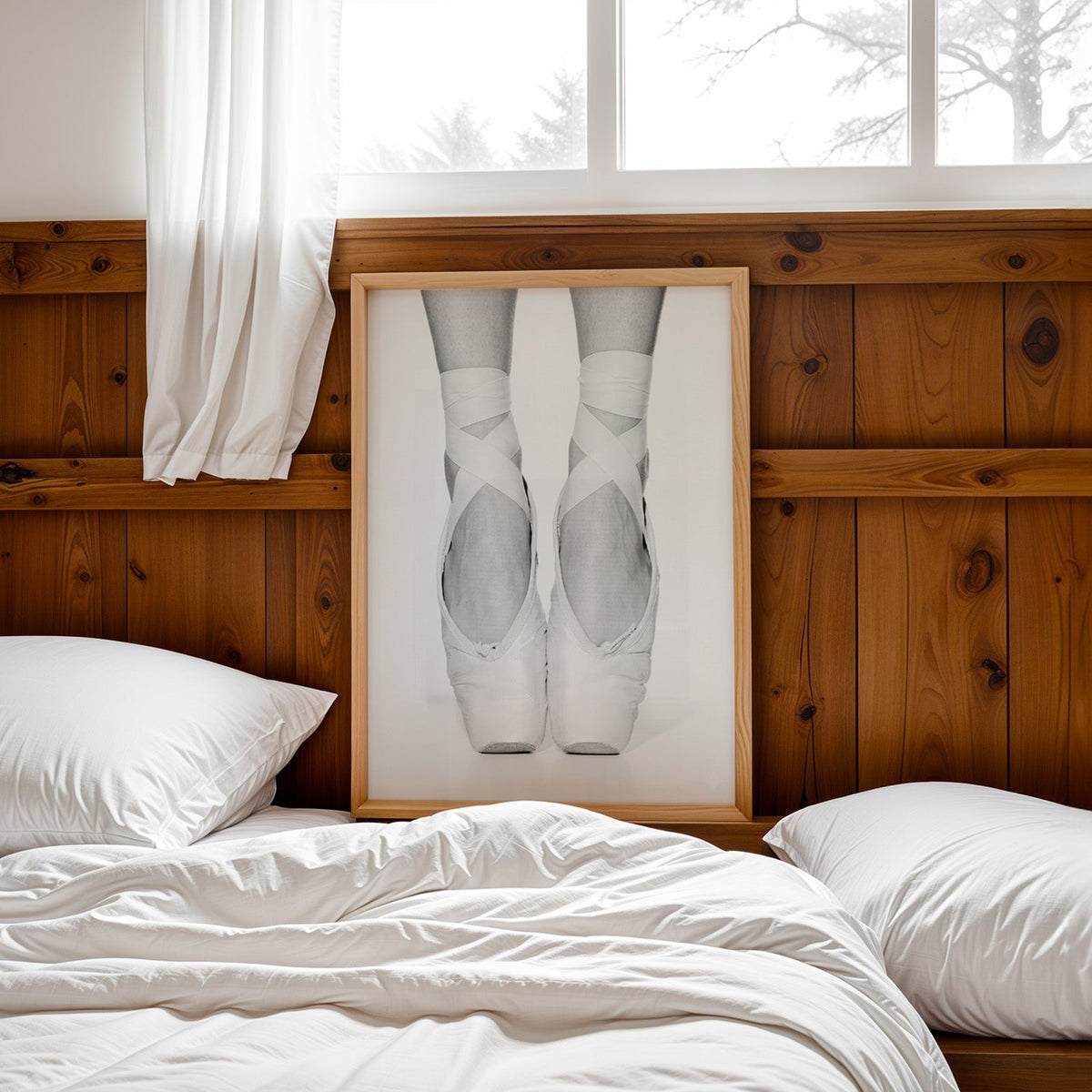 White pointe shoes with crossed ribbons close-up print in a pine frame leaning on a wood headboard over white bedding