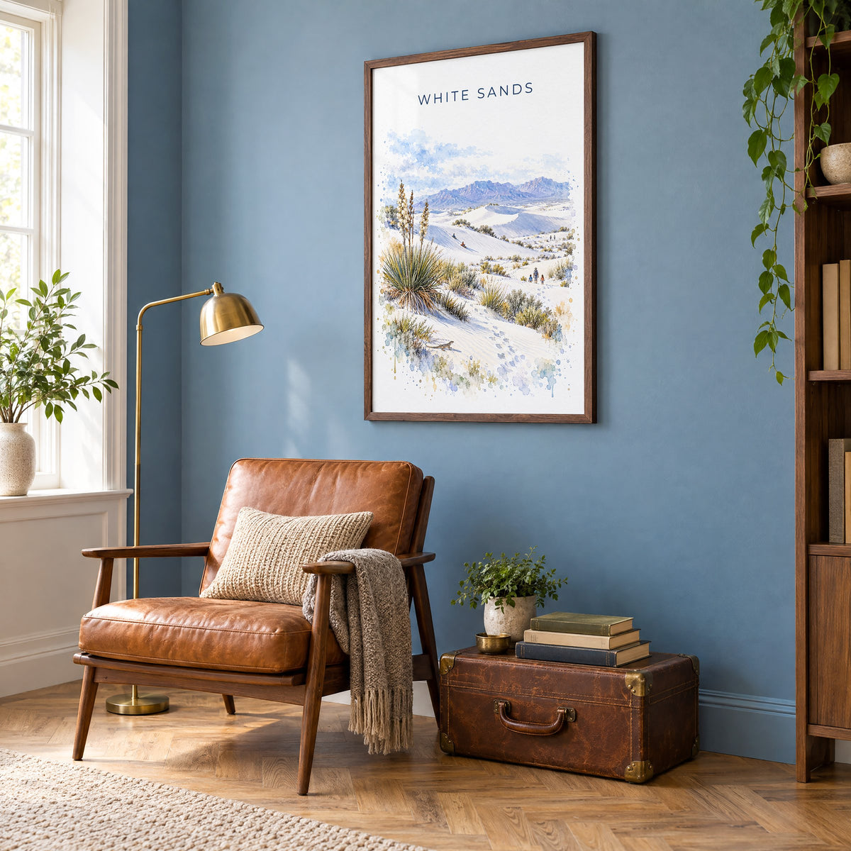 White Sands National Park watercolor print in a walnut frame on a blue wall above a leather armchair in a reading nook