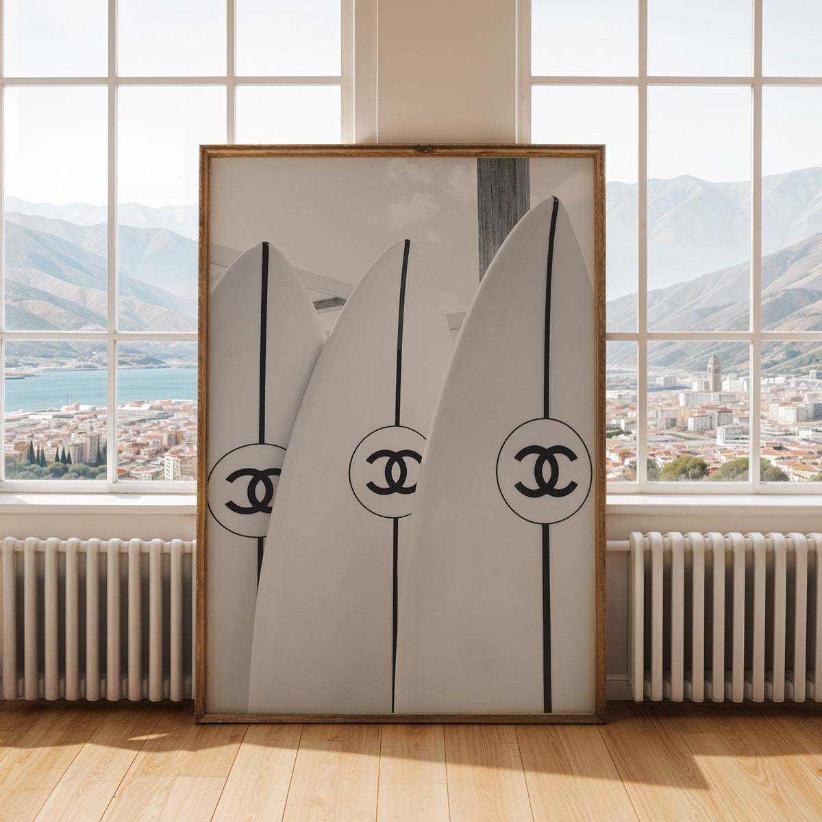 Three white surfboards with black stripes print shown in an antique gold frame by tall windows with a sea view