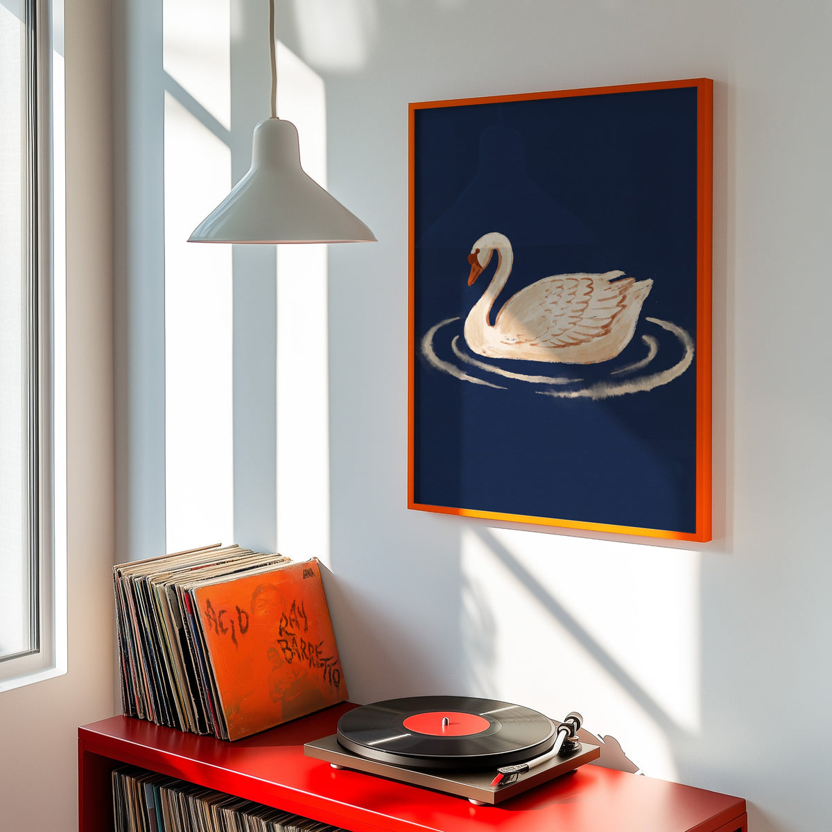 Navy swan wall art print shown in an orange frame above a red record cabinet and turntable
