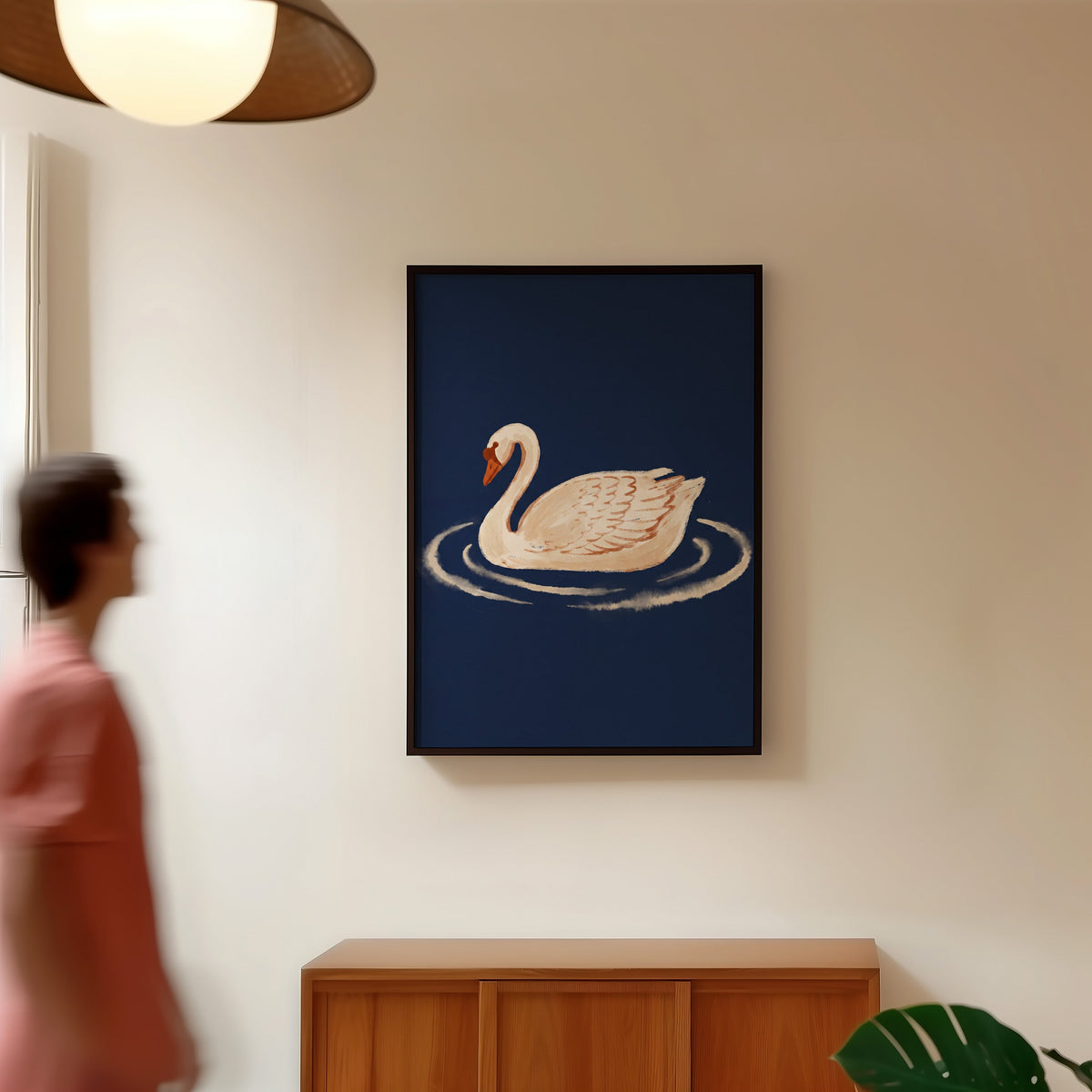 Swan and ripples print in a black frame in a hallway under a rattan pendant