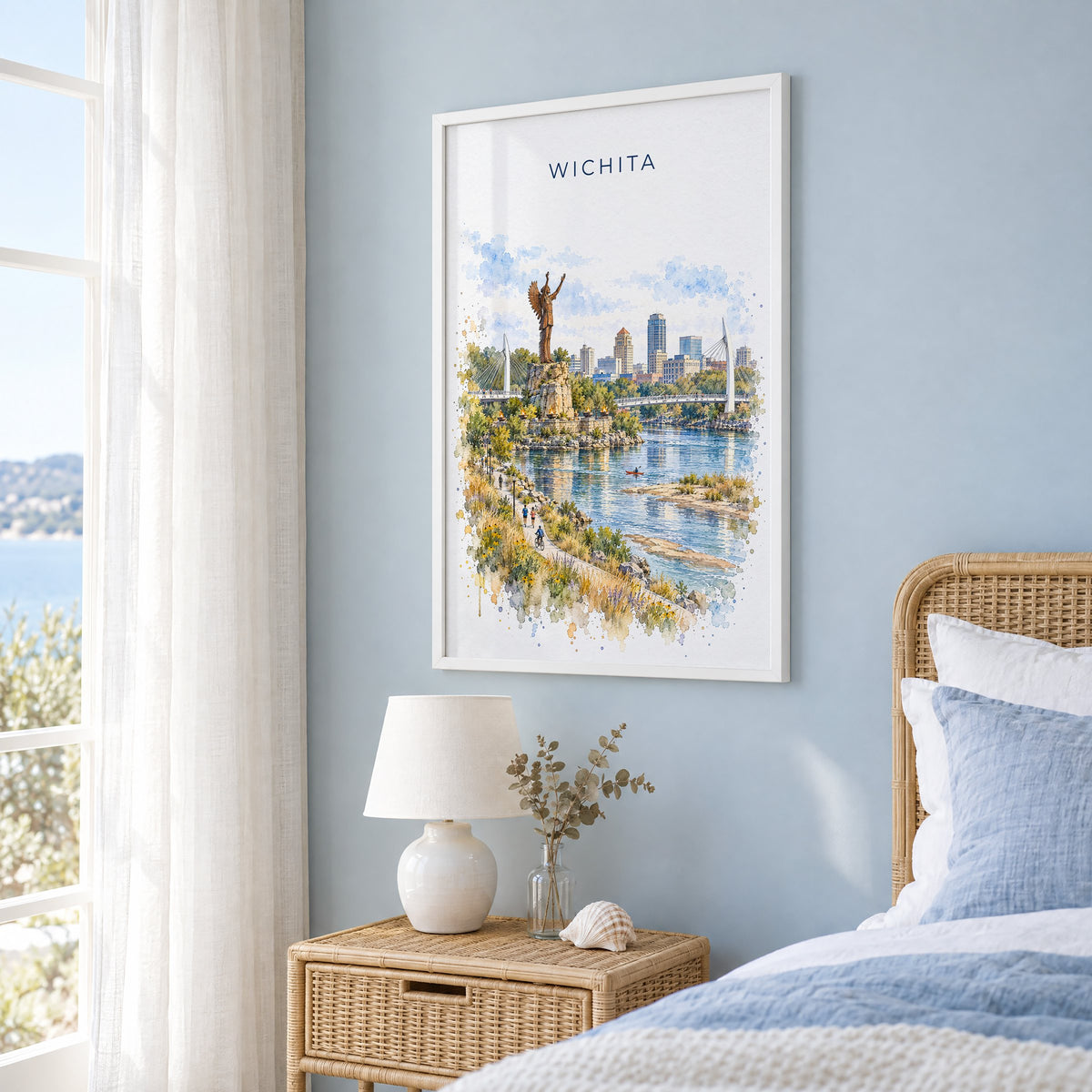 Wichita watercolor print in a white frame on a pale blue wall beside a rattan bed in a coastal bedroom
