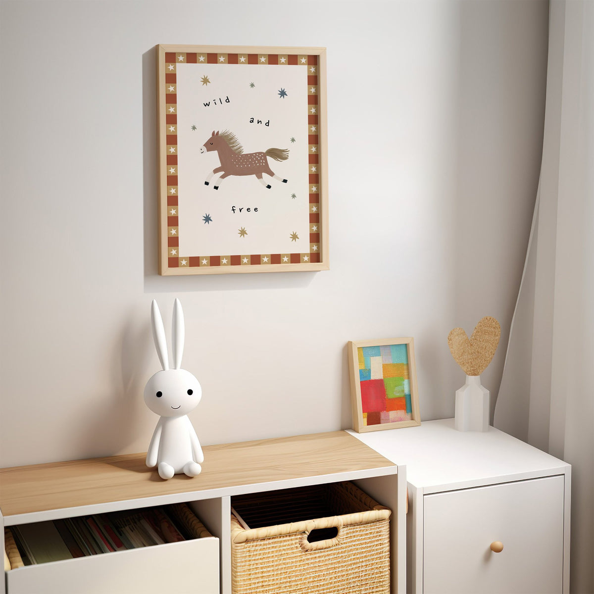 Wild and free pony nursery print in an oak frame above a kids cubby shelf with a woven basket and bunny lamp