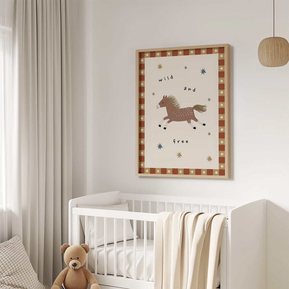 Wild and free pony nursery print in an oak frame above a white crib with a teddy bear