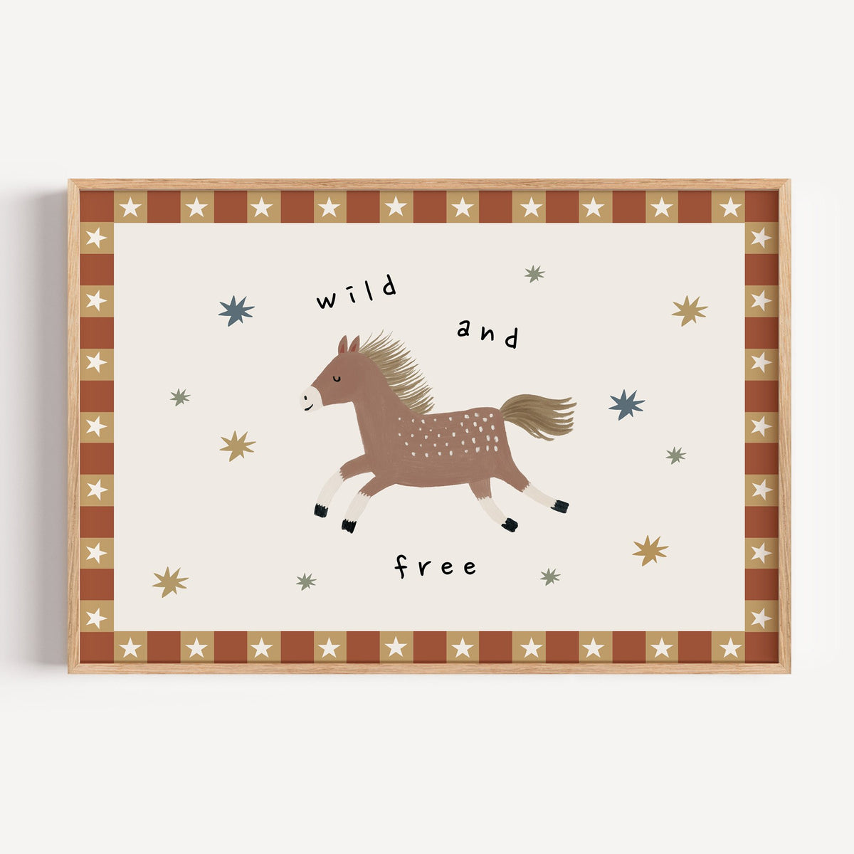 Landscape wild and free pony nursery print in a light oak frame on a plain white wall