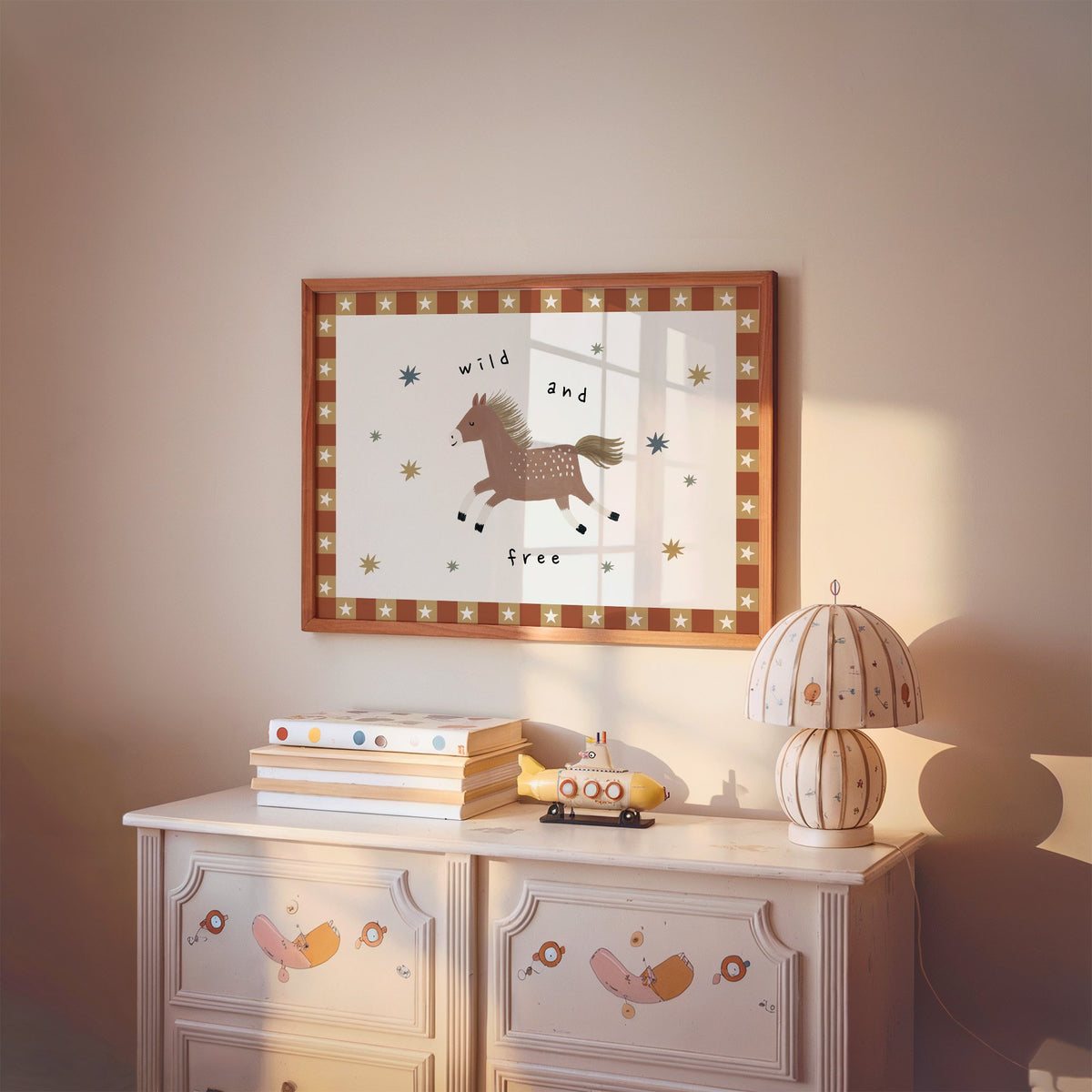 Landscape wild and free pony nursery print in a cherry wood frame above a painted dresser and lamp