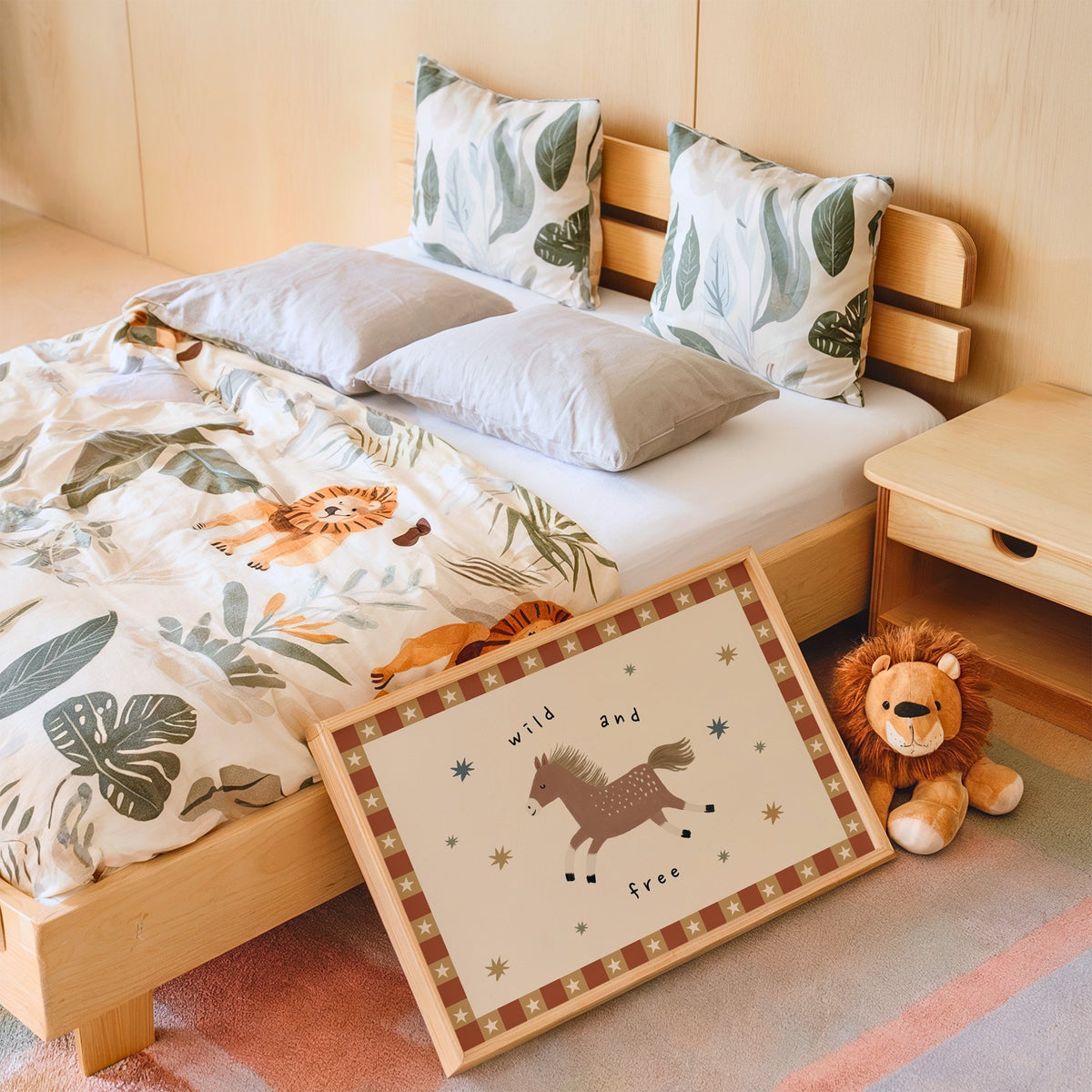 Landscape wild and free pony nursery print in an oak frame leaning on a kids bed by a lion plush