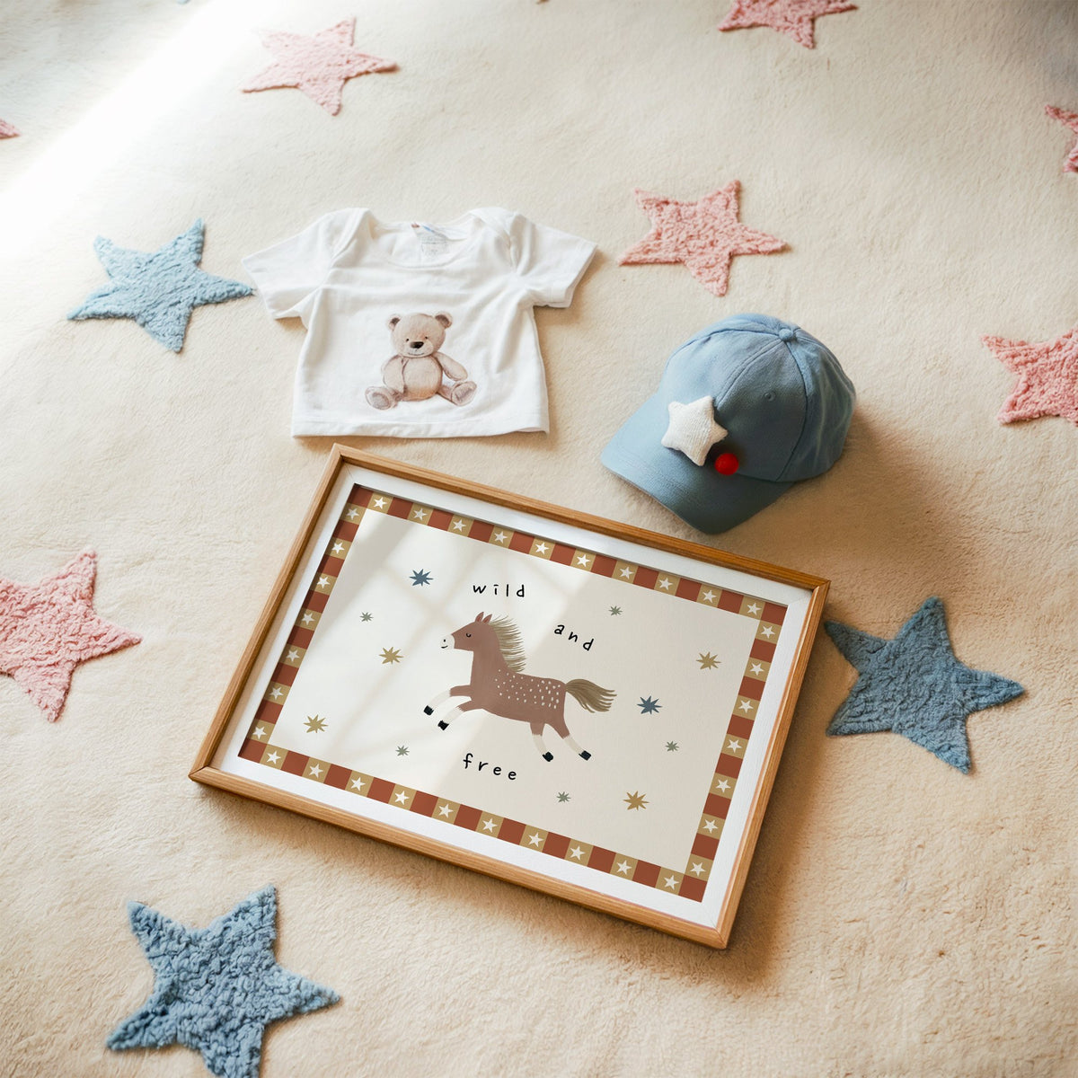 Landscape wild and free pony nursery print in a matted oak frame on a star rug with a baby tee