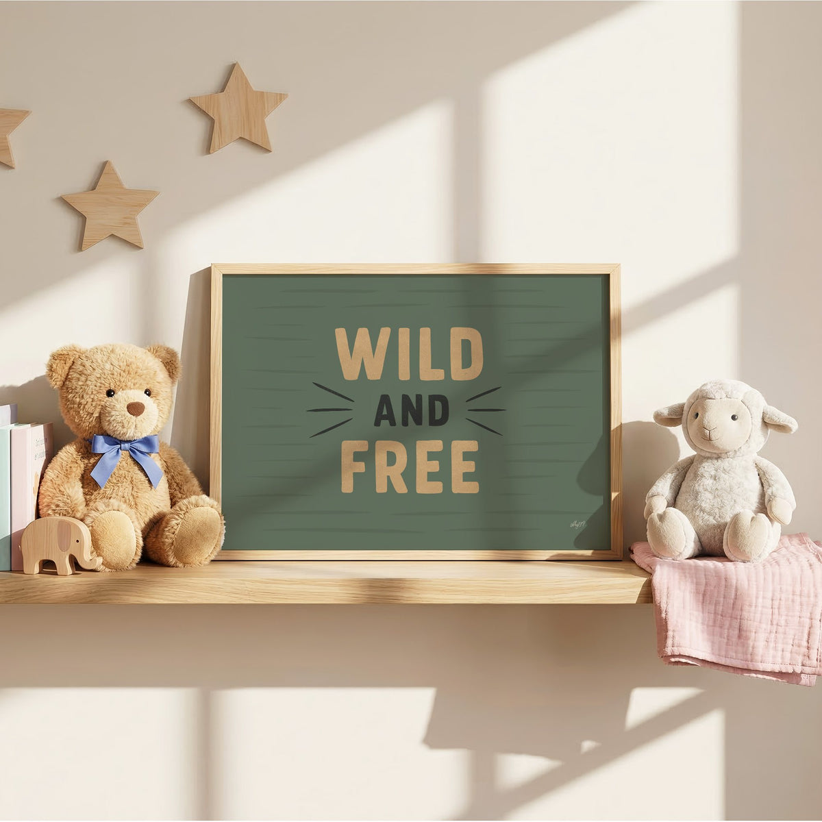 Wild and free sage green quote nursery print in an oak frame on a wall shelf between a teddy bear and a toy lamb