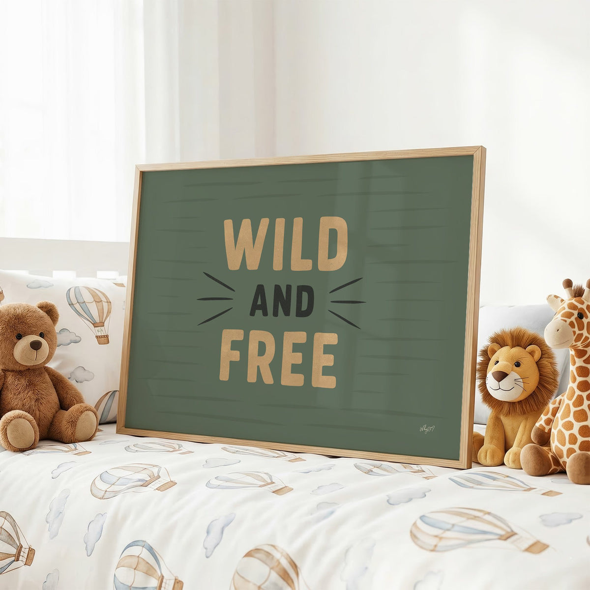 Wild and free sage green quote nursery print in an oak frame on a kids bed with hot air balloon bedding