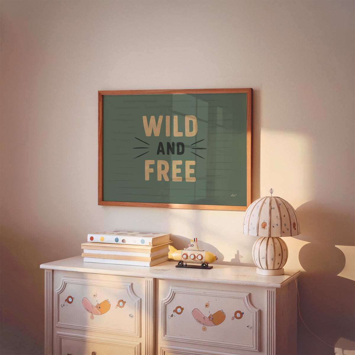 Wild and free sage green quote nursery print in a cherry wood frame above a painted dresser and lamp
