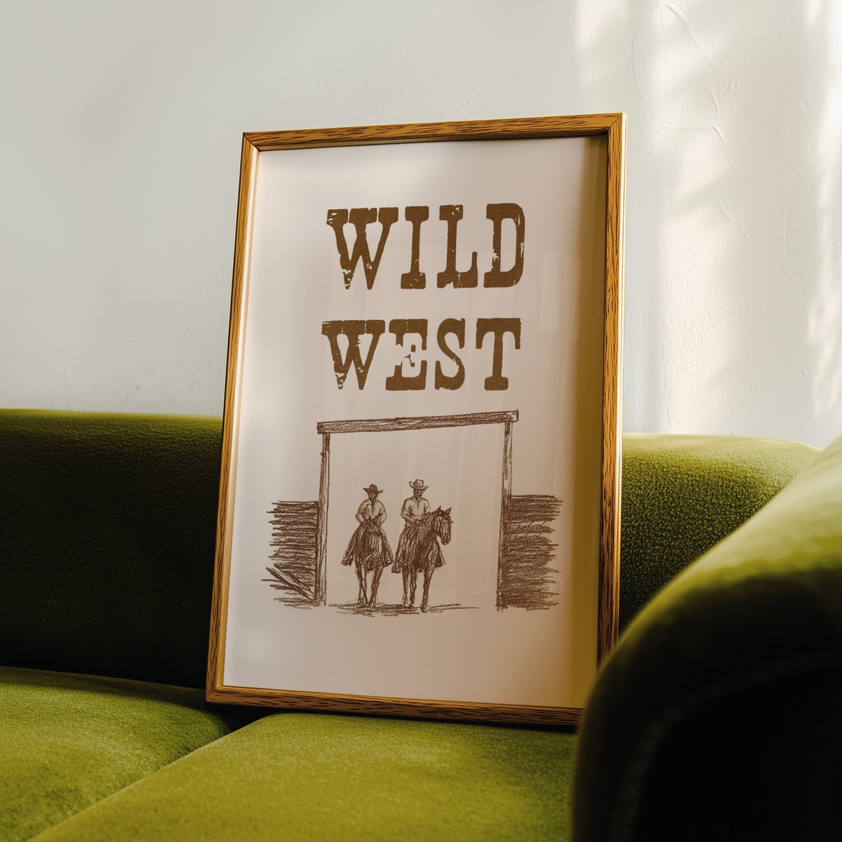 Wild West ranch gate print in an oak frame leaning on a green velvet sofa
