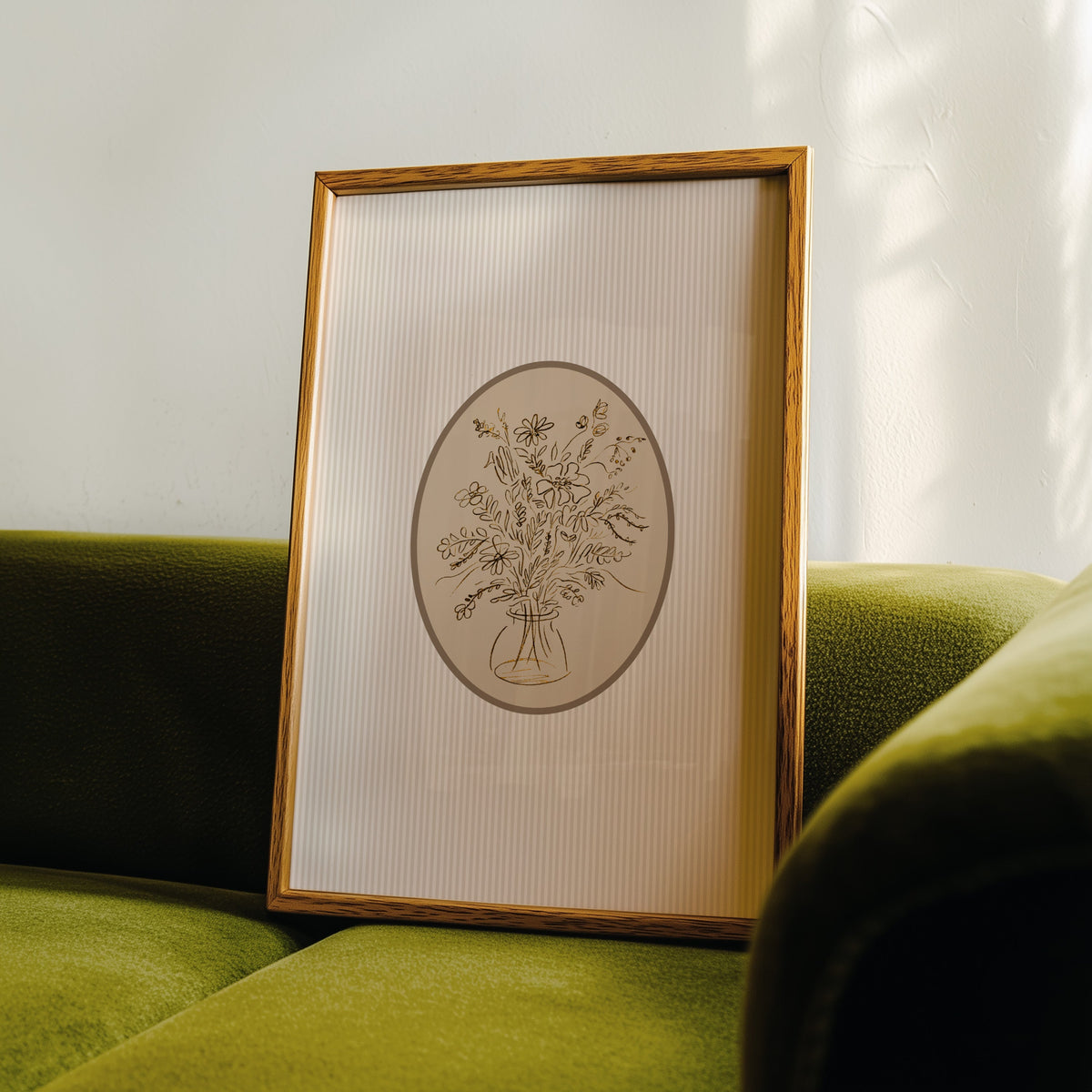 Wildflower bouquet print in an oak frame leaning on a green velvet sofa