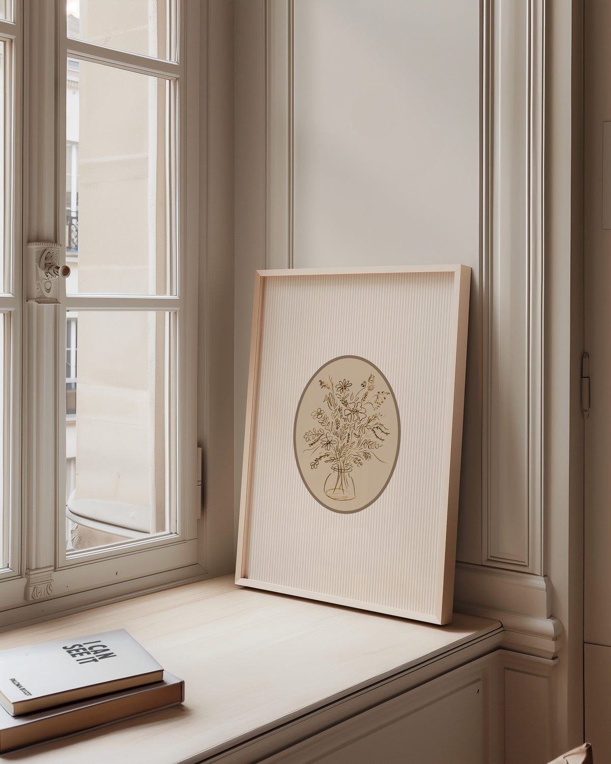 Wildflower bouquet print in a pale wood frame on a sunlit window ledge
