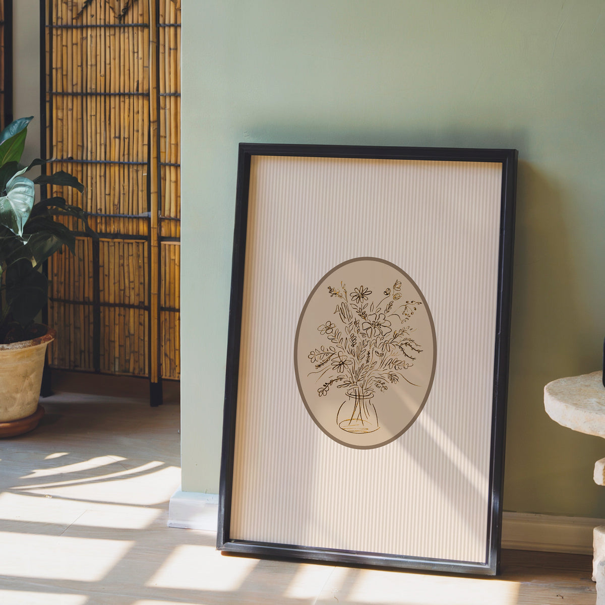 Wildflower bouquet print in a black frame leaning against a sage green wall