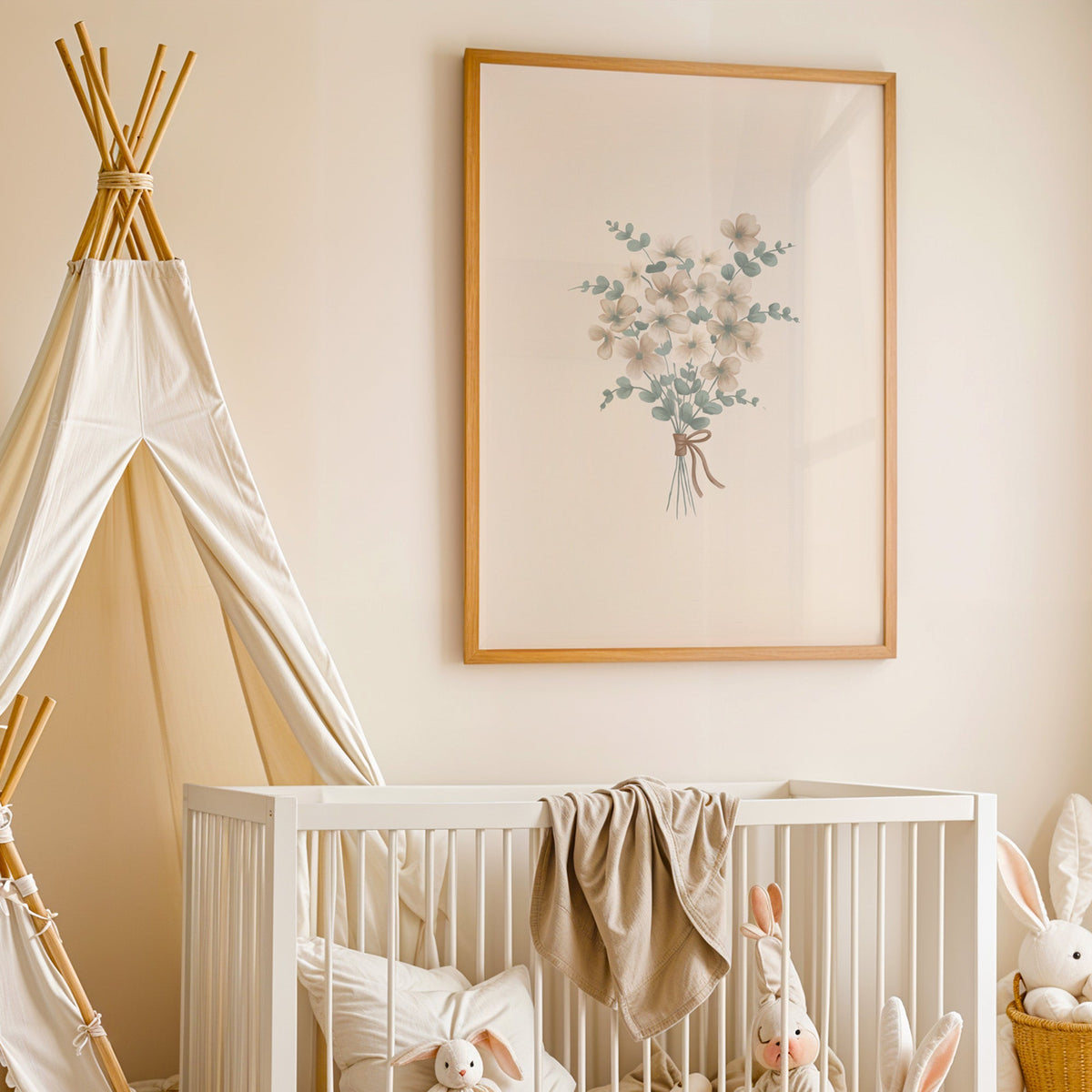 Wildflower and eucalyptus bouquet with bow nursery print in an oak frame above a white crib beside a canvas teepee