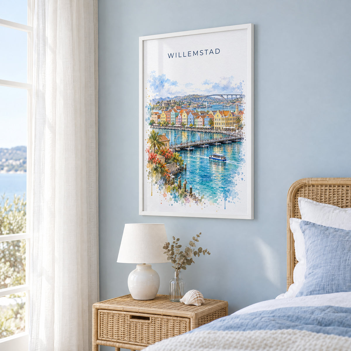 Willemstad watercolor print in a white frame on a pale blue wall beside a rattan bed in a coastal bedroom