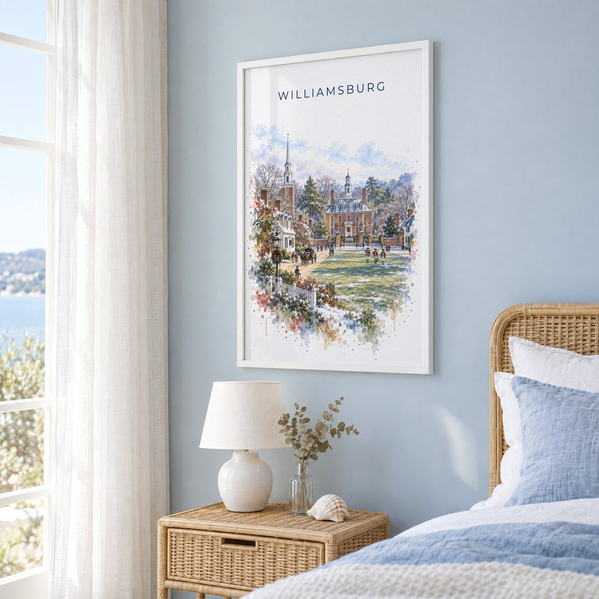 Williamsburg, Virginia watercolor print in a white frame on a pale blue wall beside a rattan bed in a coastal bedroom