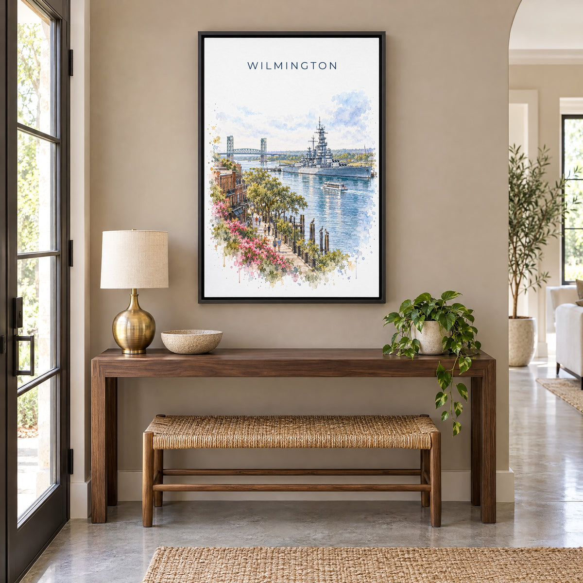 Wilmington, North Carolina watercolor print as a black floater canvas above a walnut console and woven bench in an entryway