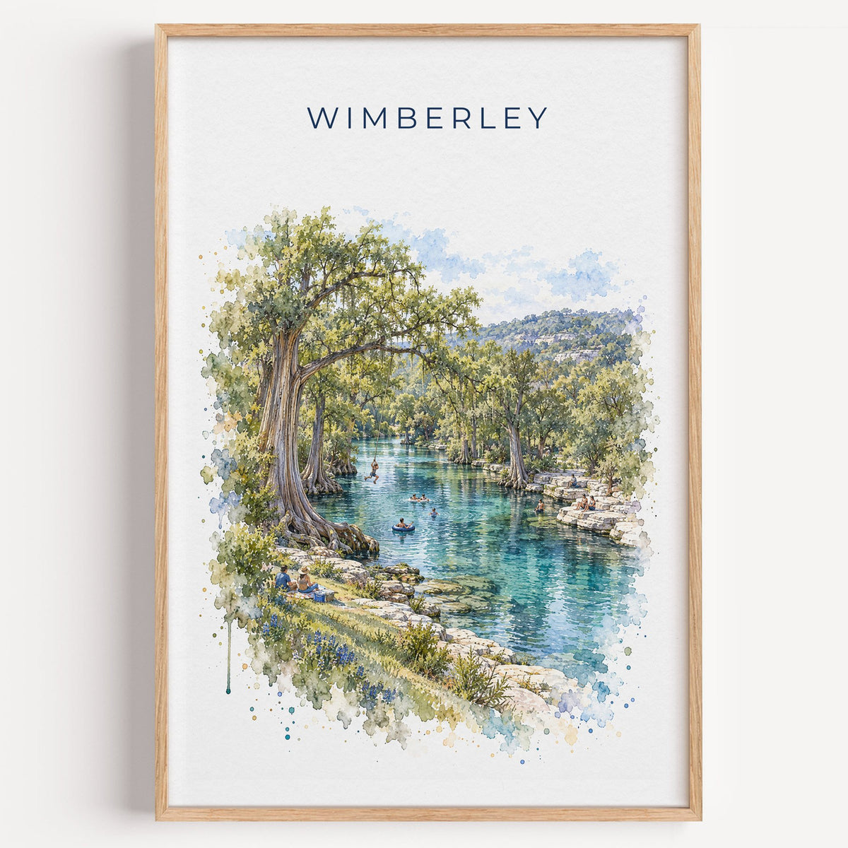 Wimberley, Texas watercolor print in a light oak frame on a plain white wall