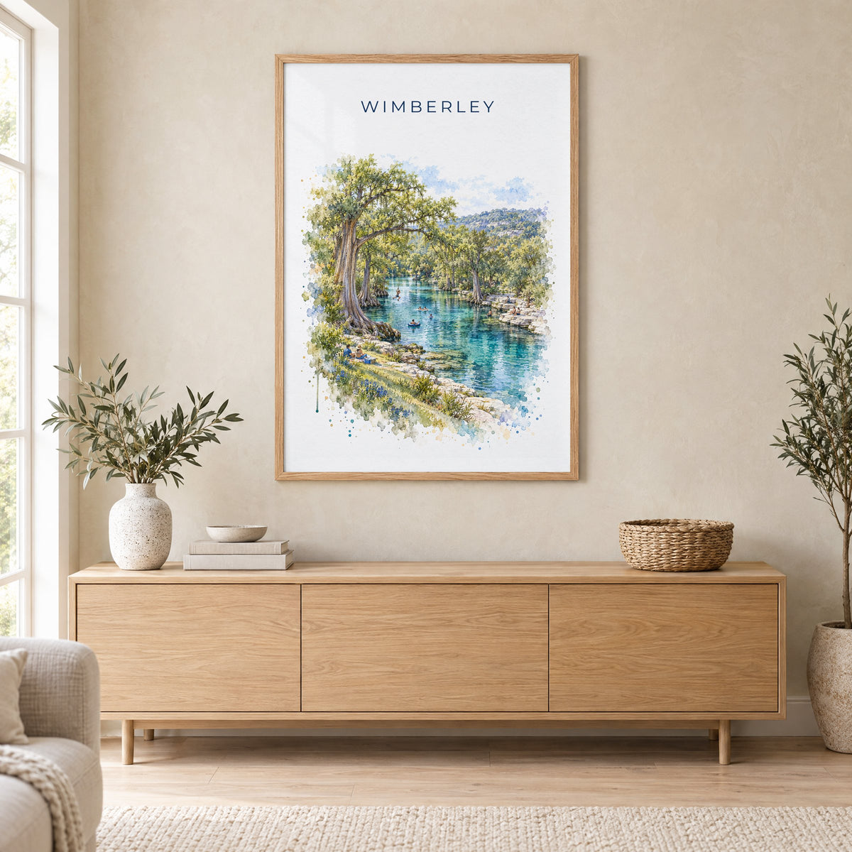 Wimberley, Texas watercolor print in an oak frame above a light wood sideboard in a Scandinavian living room