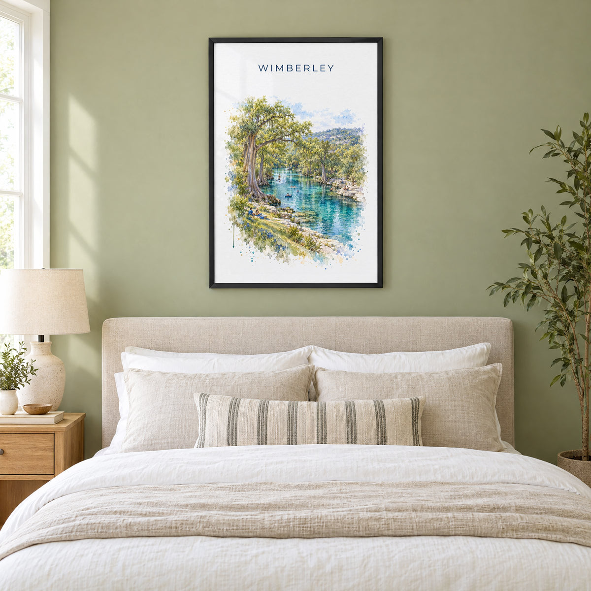 Wimberley, Texas watercolor print in a black frame above an upholstered headboard in a sage green bedroom