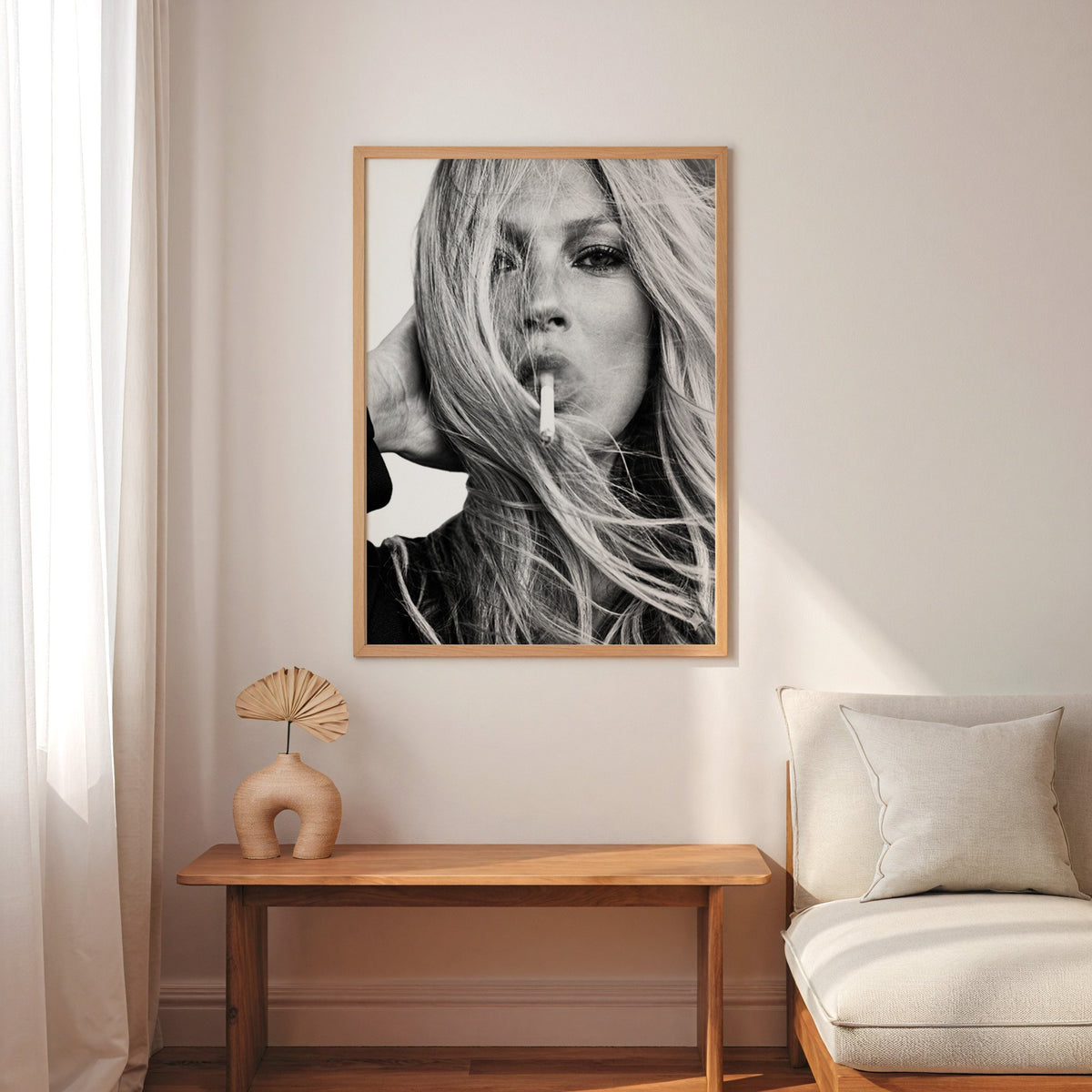 Woman with windswept hair across her face print in an oak frame above a narrow console with an arched vase
