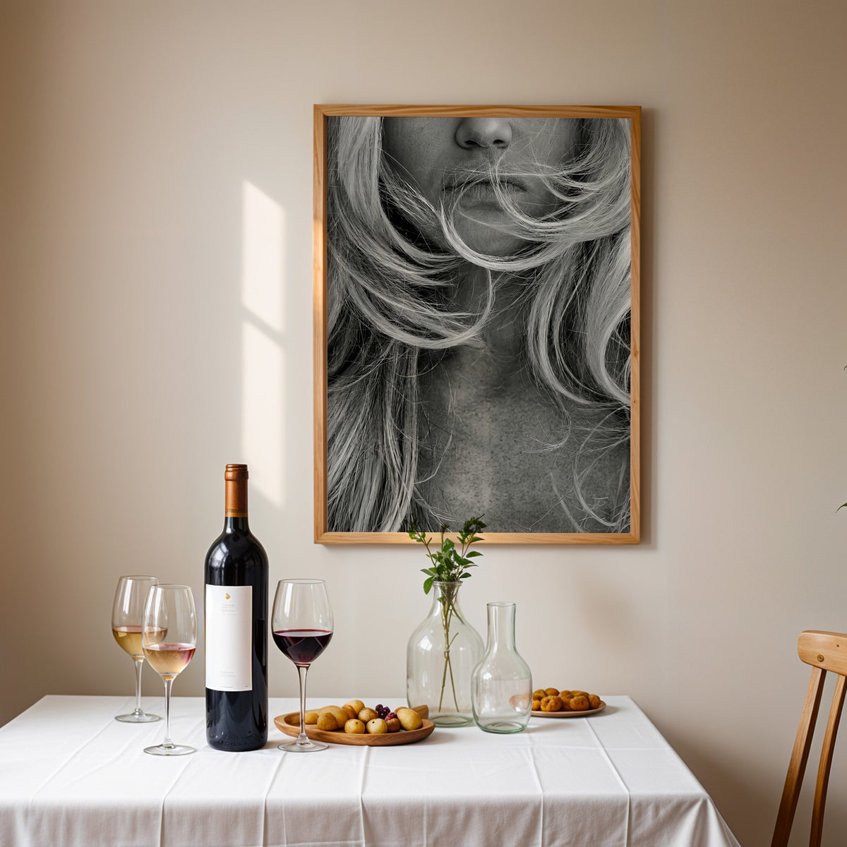 Windswept blonde hair over lips closeup print in an oak frame above a table set with red wine and glasses