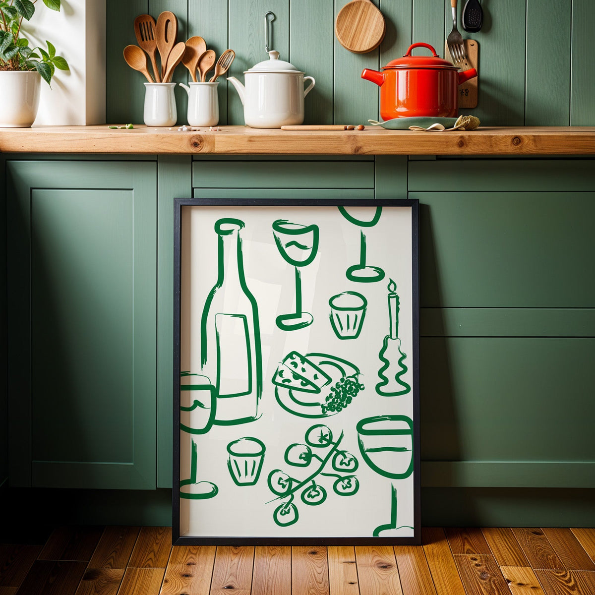 Wine and cheese green pattern print in a black frame against sage green cabinets