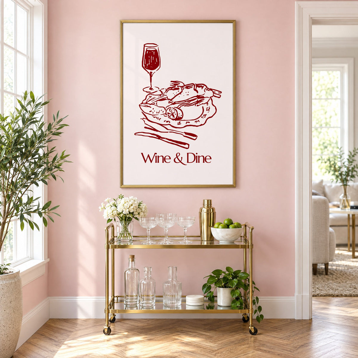 Wine & Dine roast plate burgundy sketch print in a brass frame on a blush pink wall above a gold bar cart with glassware
