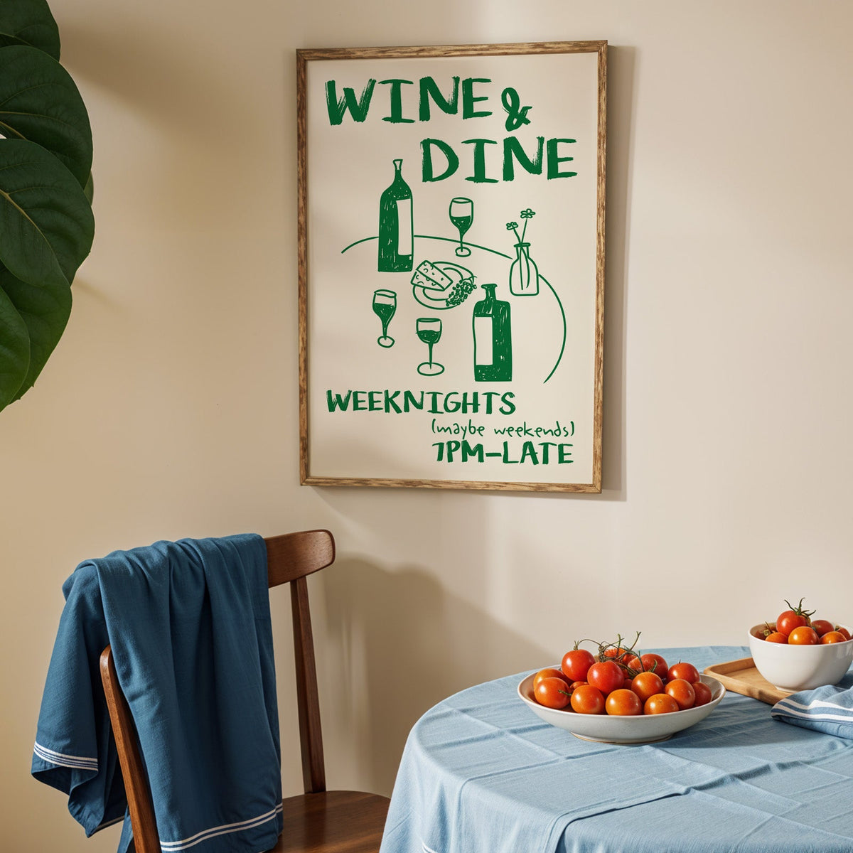 Wine and dine table print in an oak frame above a blue linen table with tomatoes