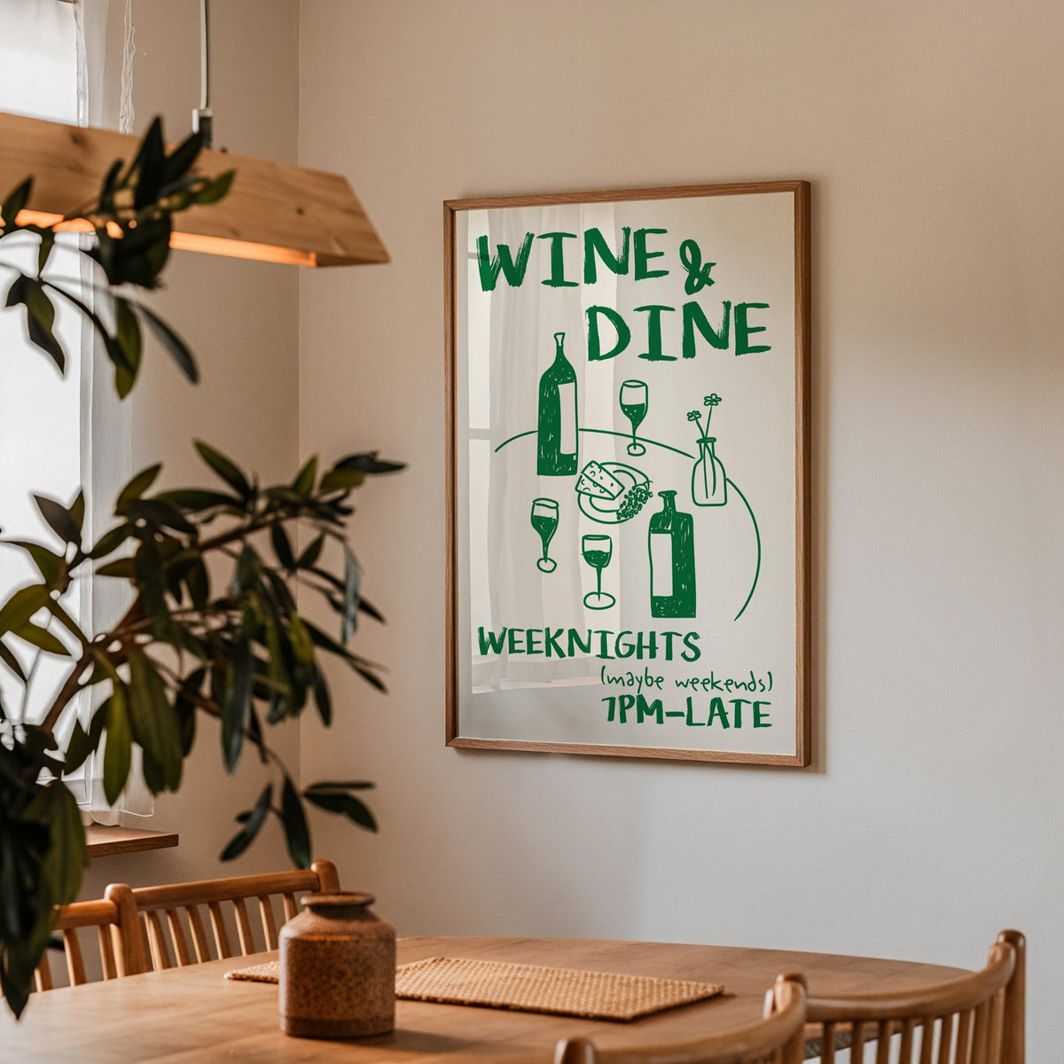 Wine and dine table print in a walnut frame above a table beside an olive tree