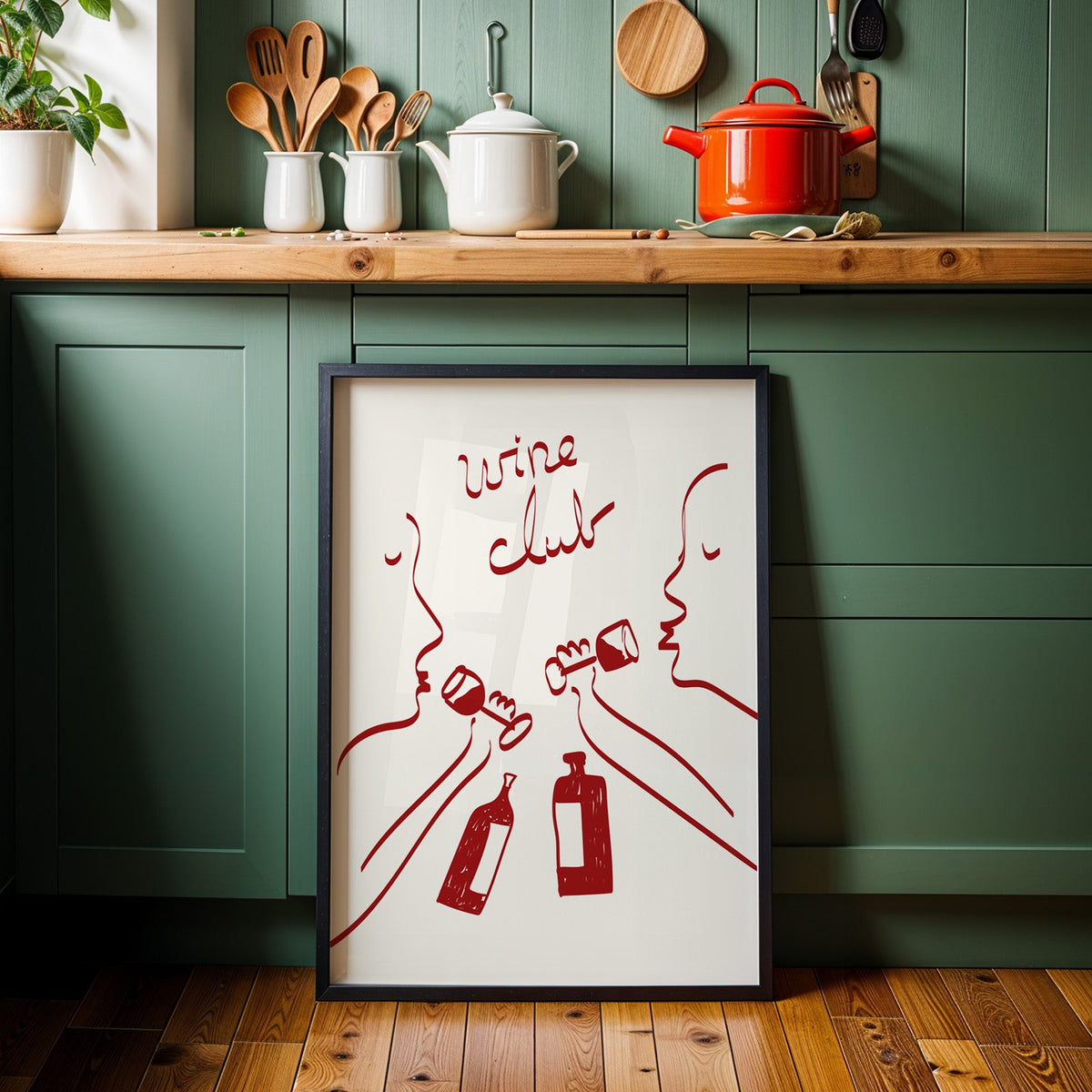 Wine club faces line art print in a black frame against sage green cabinets