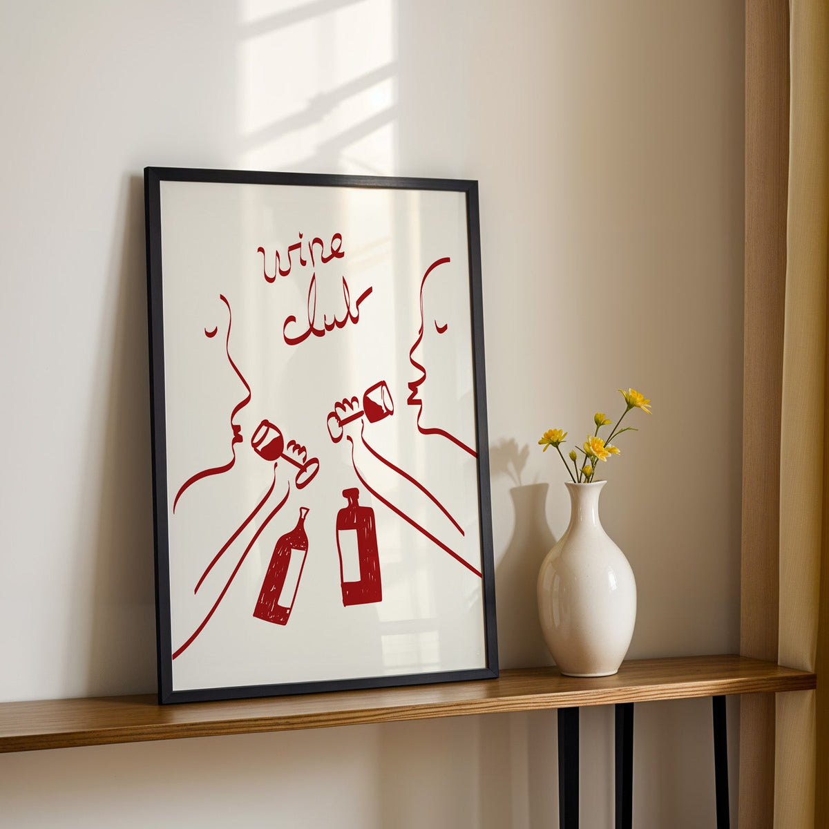 Wine club faces line art print in a black frame on a console table with daisies