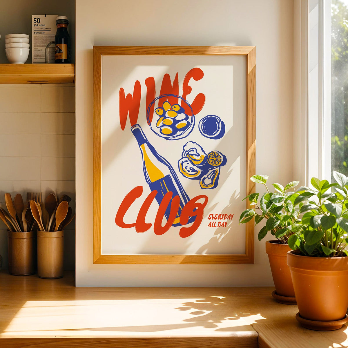 Wine Club oysters print in a light pine frame beside a ceramic jar of wooden spoons
