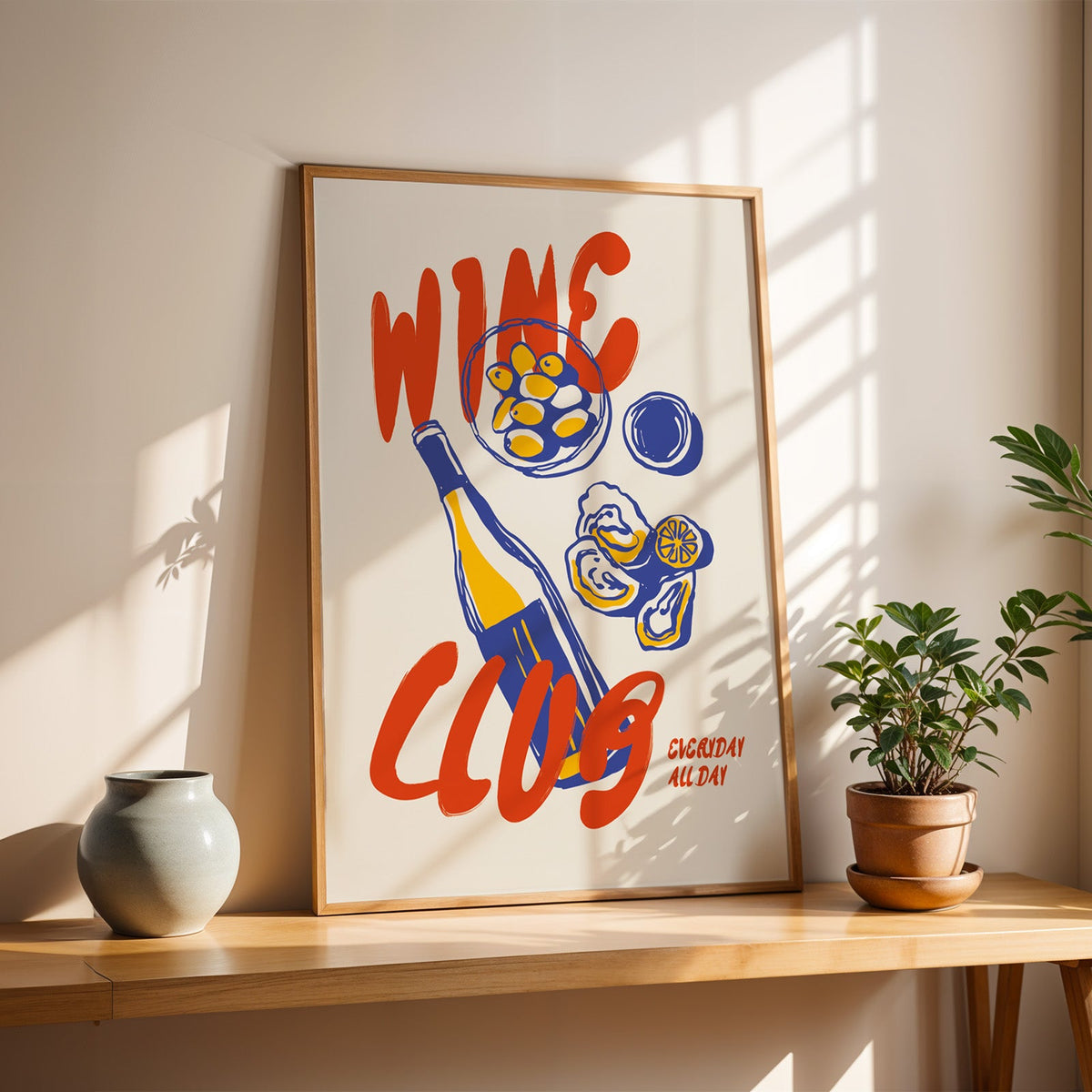 Wine Club oysters print in a slim oak frame on a console with a grey-blue vase