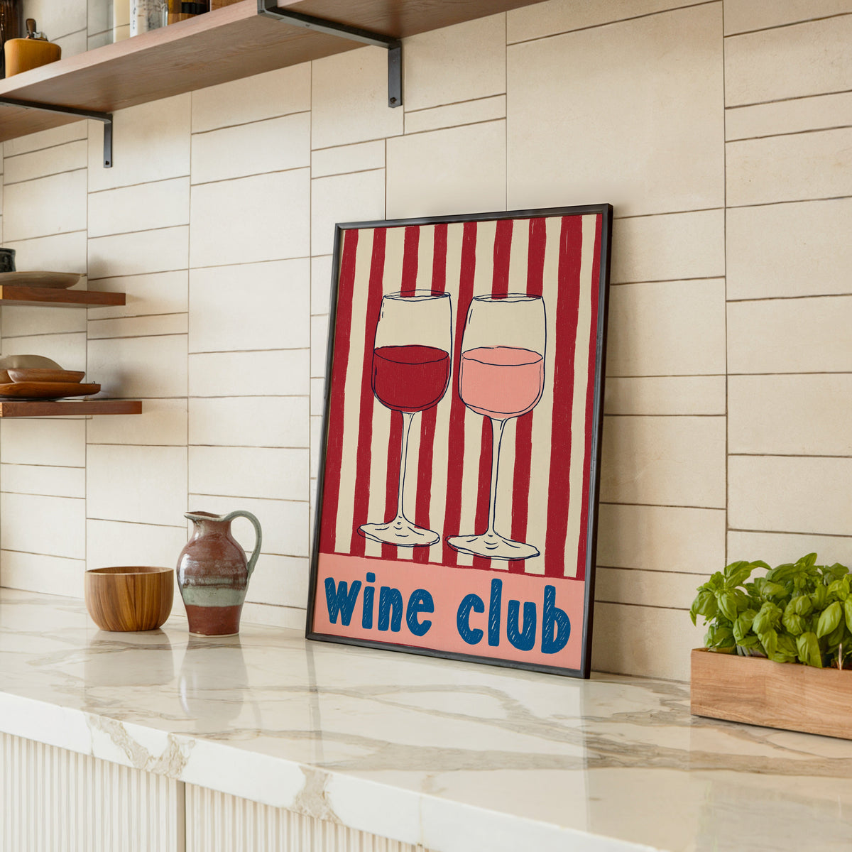 Wine Club print in a black frame leaning on a marble counter in a tiled kitchen