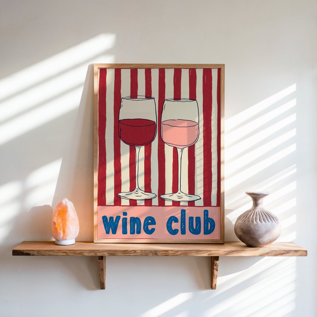 Wine Club print in an oak frame on a live-edge shelf beside a salt lamp