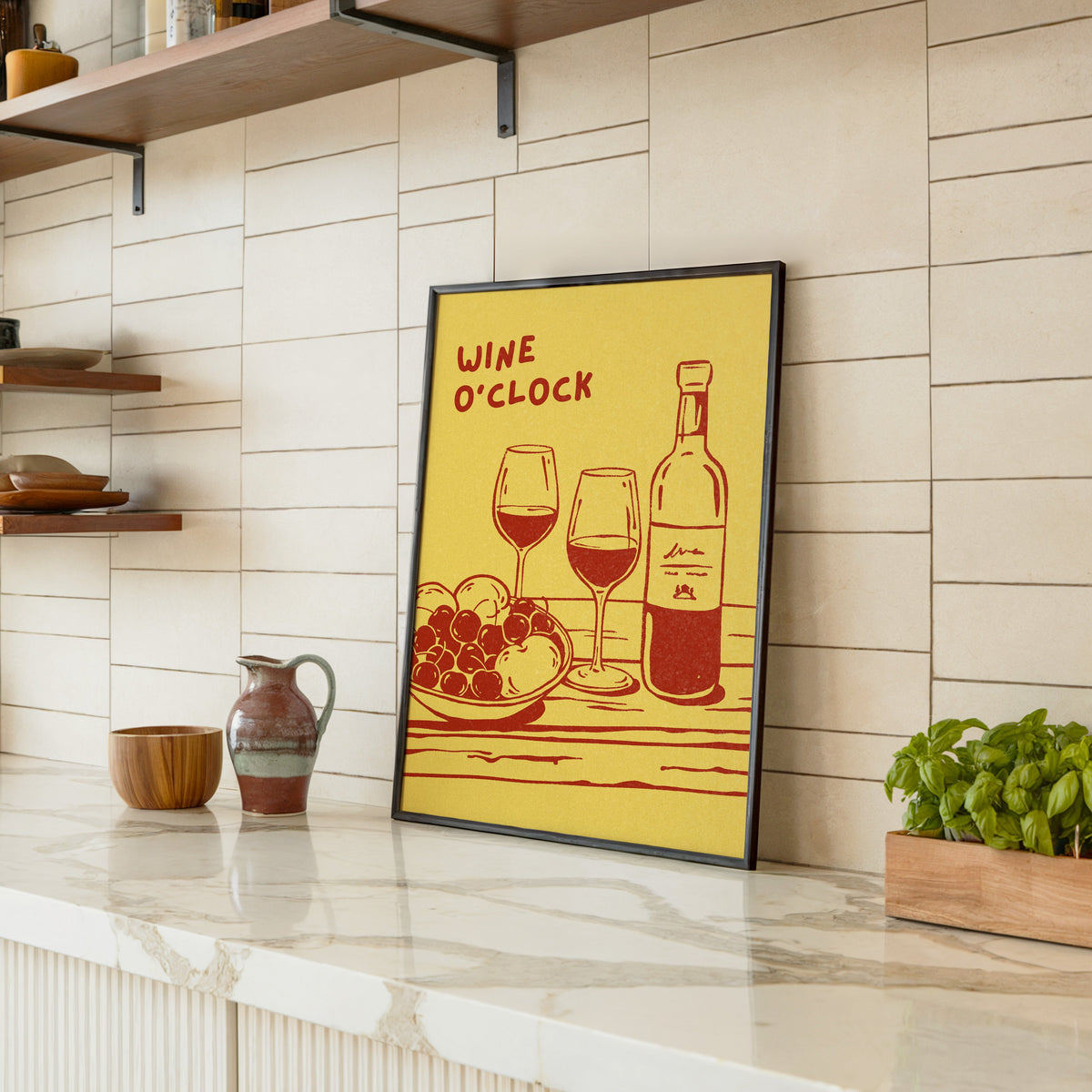 Wine O'Clock print in a black frame leaning on a marble counter in a tiled kitchen