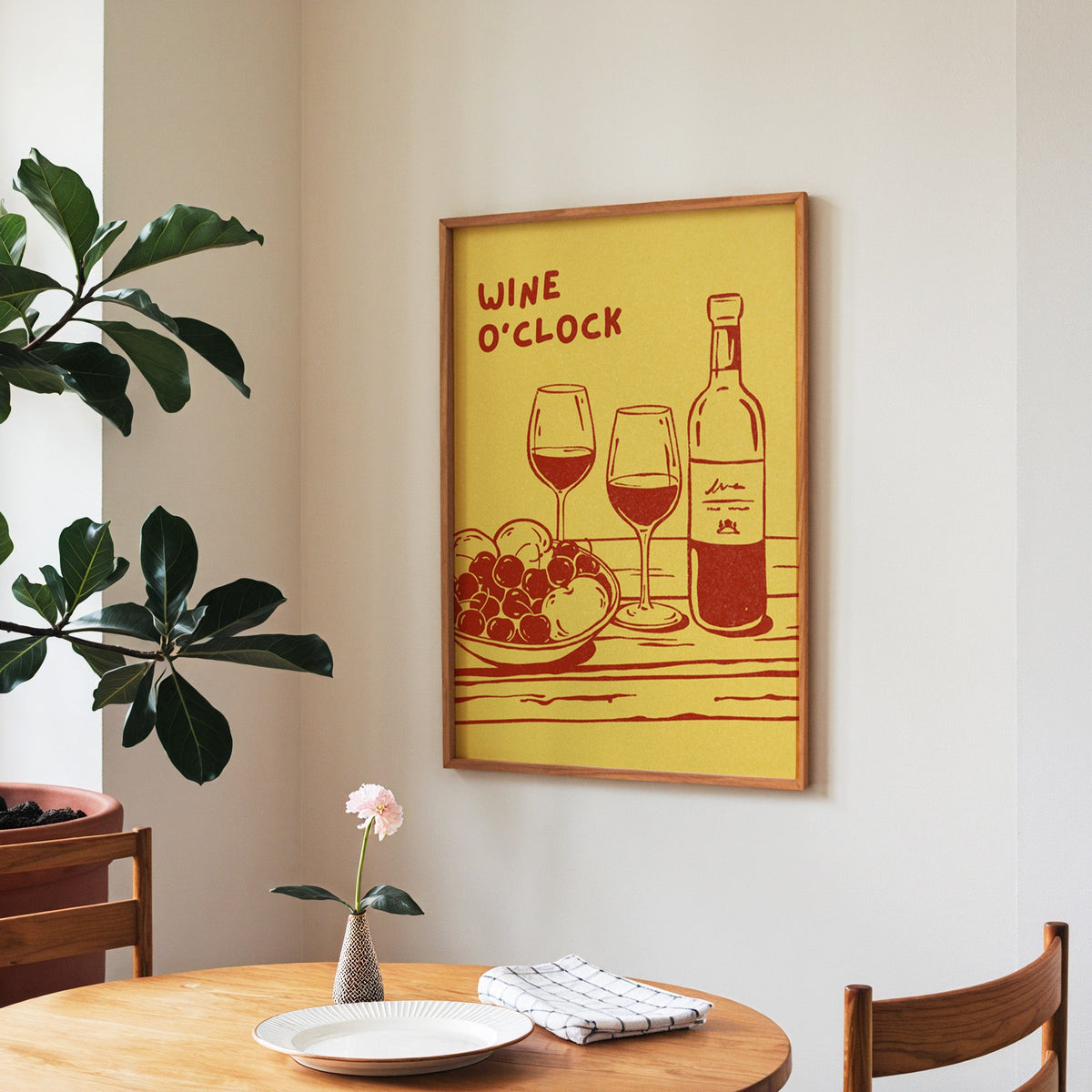 Wine O'Clock print in a walnut frame above a round table beside a fiddle-leaf fig