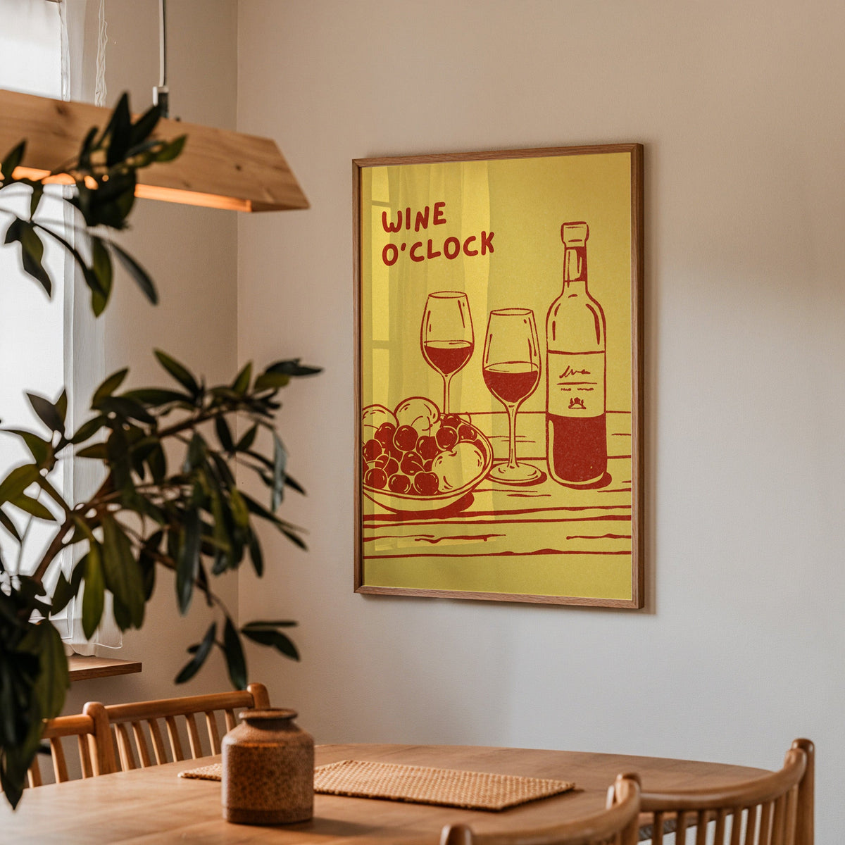 Wine O'Clock print in a walnut frame above a dining table with olive branches