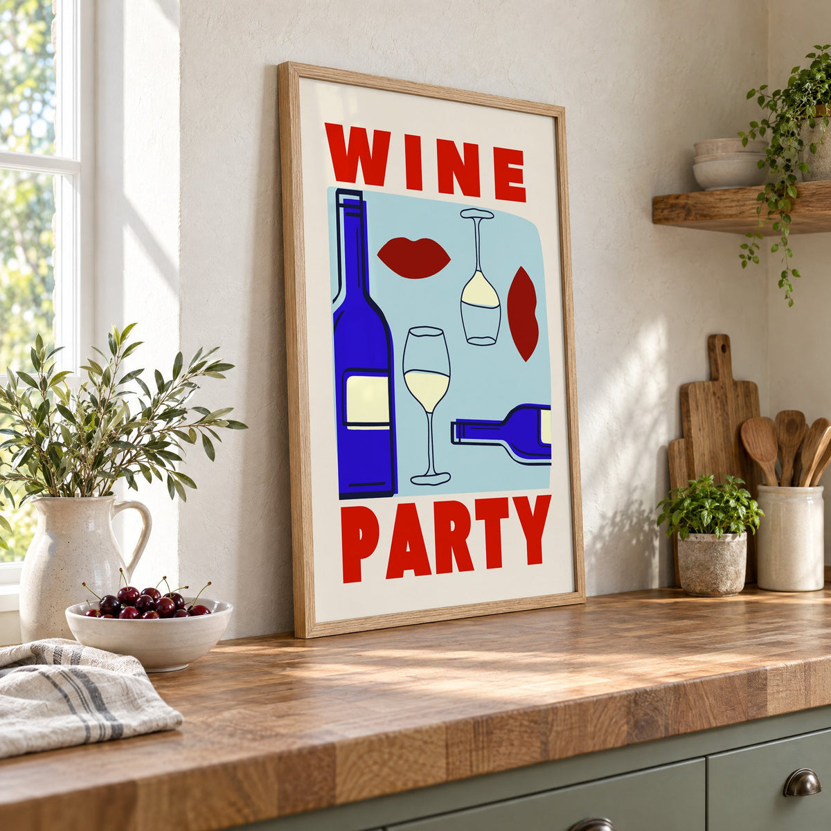 Wine Party bottles and red lips print in an oak frame leaning on a butcher block island beside a bowl of cherries
