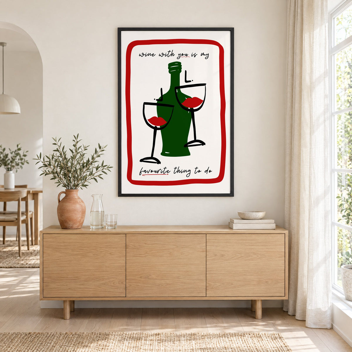 Wine with you lip glasses print in a black frame above an oak sideboard with a terracotta vase of olive branches