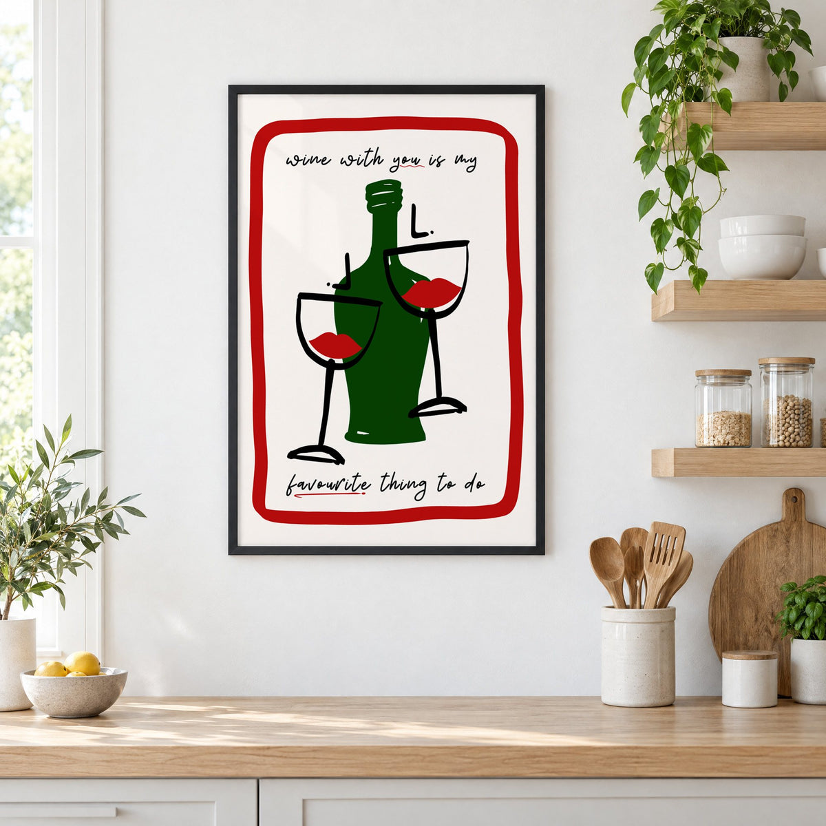 Wine with you lip glasses print in a black frame in a white kitchen beside open wood shelves and glass jars